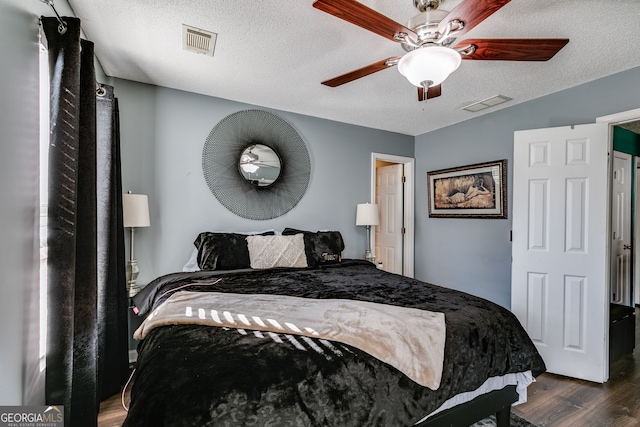 bedroom with ceiling fan, dark hardwood / wood-style floors, and a textured ceiling