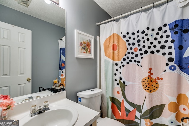 bathroom featuring a textured ceiling, toilet, vanity, and walk in shower