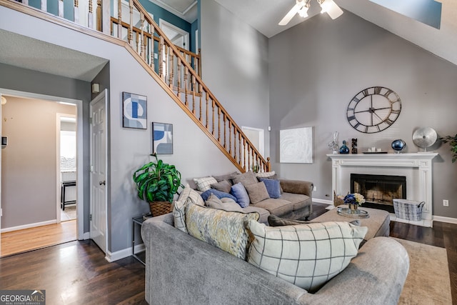 living room with ceiling fan, dark wood-type flooring, and a towering ceiling