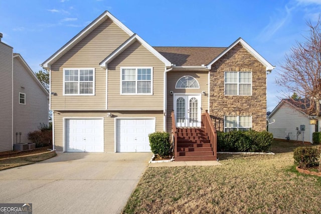 split foyer home featuring a garage, cooling unit, and a front yard