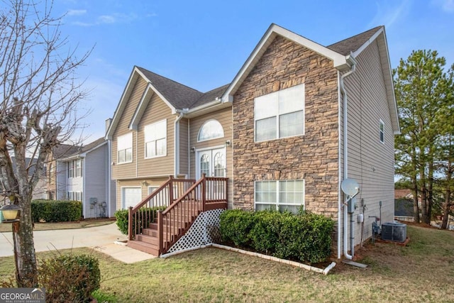 view of front of house with a garage, a front yard, and central AC unit