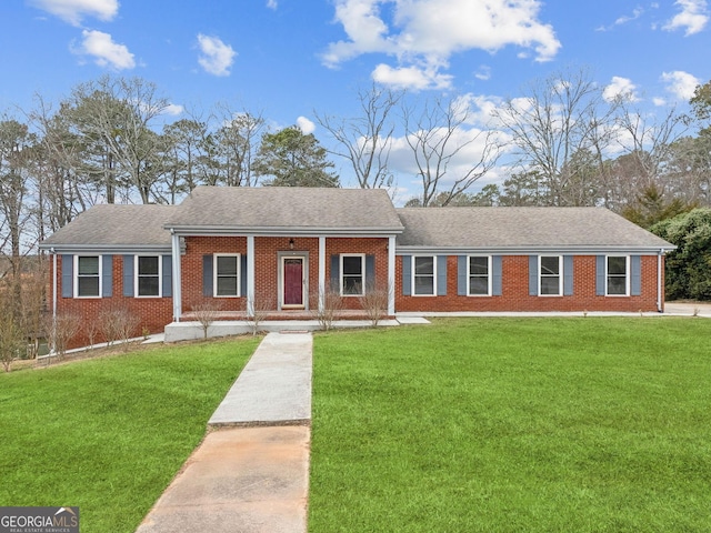 ranch-style house featuring a shingled roof, covered porch, brick siding, and a front lawn