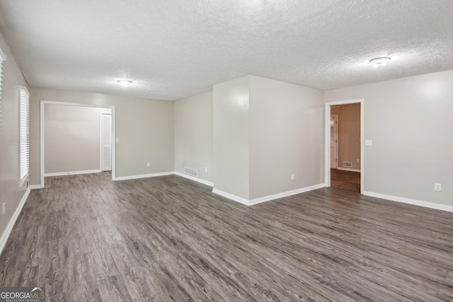 unfurnished room with dark wood finished floors, a textured ceiling, and baseboards