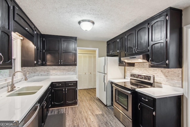 kitchen featuring light countertops, appliances with stainless steel finishes, a sink, light wood-type flooring, and under cabinet range hood