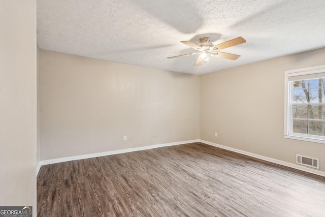 unfurnished room featuring wood finished floors, visible vents, and baseboards