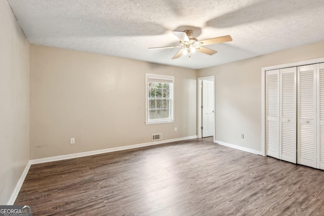 unfurnished bedroom featuring a closet, visible vents, baseboards, and wood finished floors