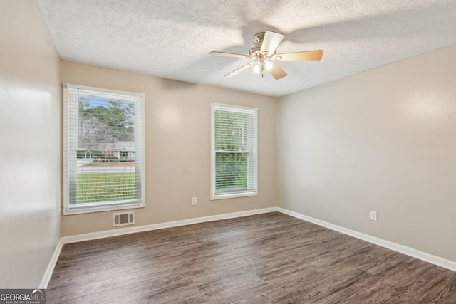 spare room with ceiling fan, wood finished floors, visible vents, and baseboards