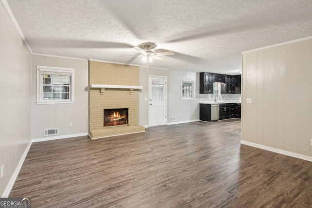 unfurnished living room featuring dark wood-style floors, visible vents, ornamental molding, and a ceiling fan