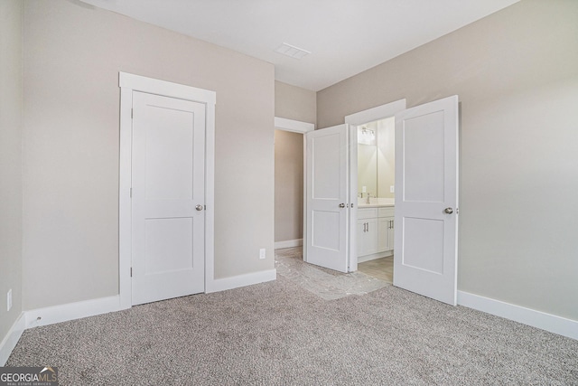 unfurnished bedroom featuring light carpet and ensuite bath