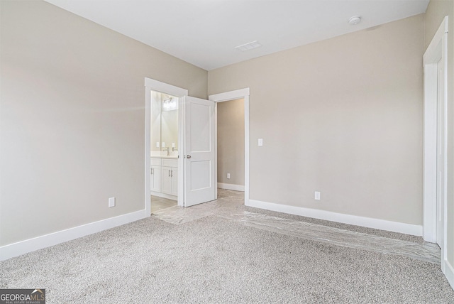 unfurnished bedroom featuring ensuite bath and light carpet