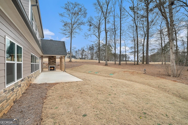 view of yard with a patio and exterior fireplace