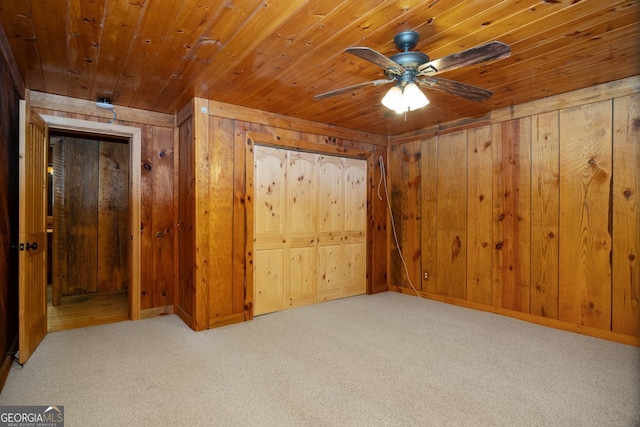 unfurnished bedroom featuring light carpet, wood ceiling, wooden walls, and ceiling fan