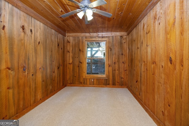 carpeted spare room with ceiling fan, wooden walls, and wooden ceiling