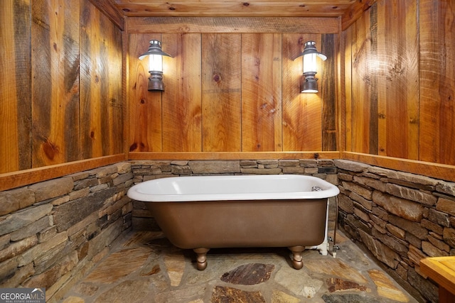 bathroom with a bathtub and wood walls