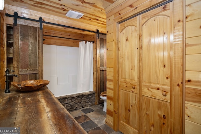 full bathroom with toilet, shower / tub combo with curtain, wooden walls, and sink