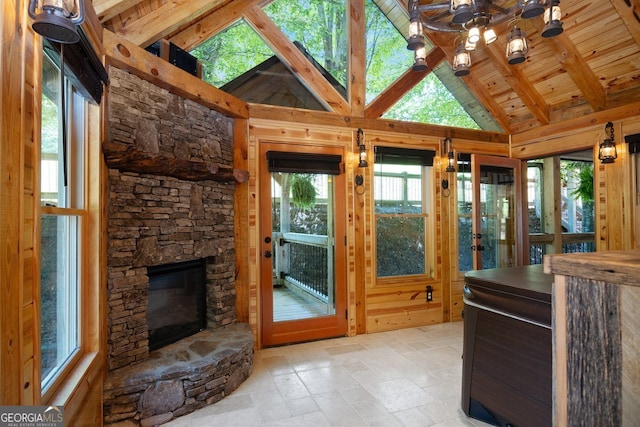 interior space with lofted ceiling with beams, a stone fireplace, and wood ceiling