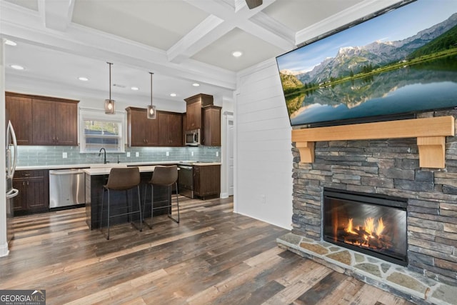 kitchen featuring stainless steel appliances, dark hardwood / wood-style floors, a center island, a kitchen breakfast bar, and decorative light fixtures