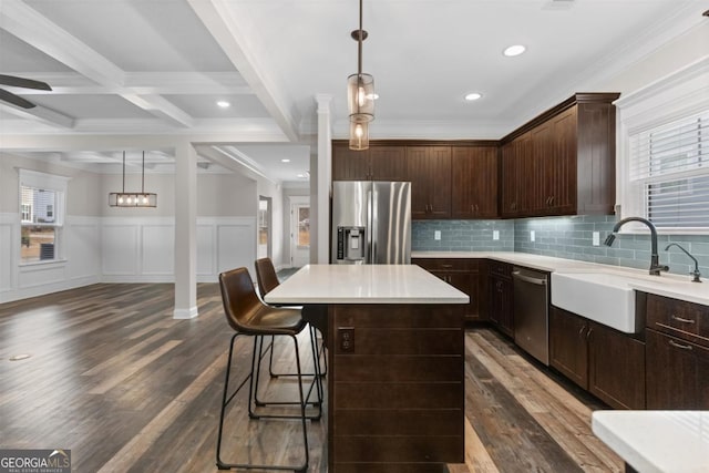 kitchen with pendant lighting, sink, a center island, stainless steel appliances, and dark brown cabinets