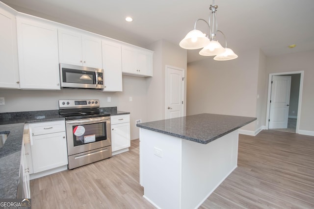 kitchen featuring white cabinetry, decorative light fixtures, stainless steel appliances, and light wood-type flooring