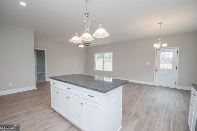 kitchen with a center island, white cabinets, dark stone counters, and decorative light fixtures