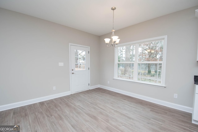 unfurnished dining area featuring a chandelier and light wood-type flooring