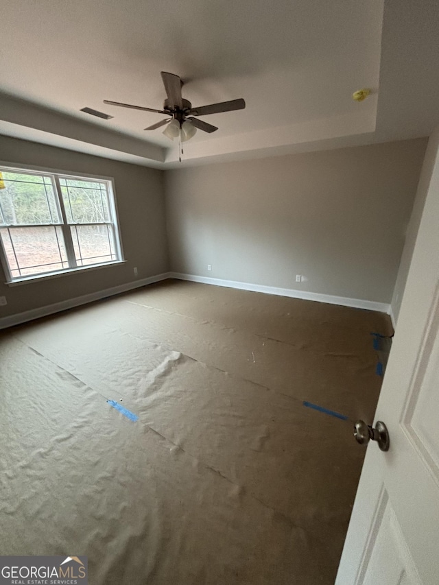 spare room with ceiling fan and a tray ceiling