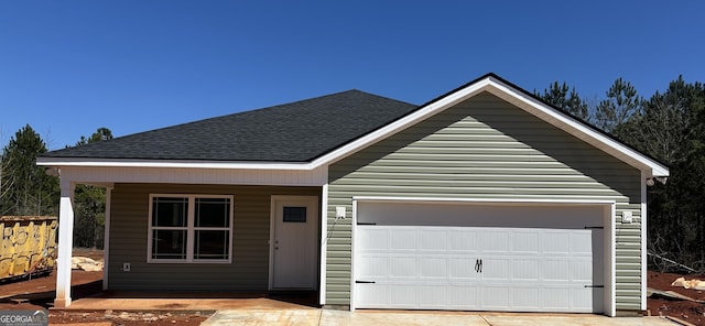 view of front of home with driveway, an attached garage, and a shingled roof