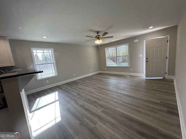 unfurnished living room with ceiling fan, dark hardwood / wood-style floors, and a healthy amount of sunlight