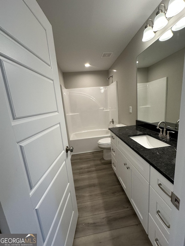 full bathroom featuring wood-type flooring, bathtub / shower combination, vanity, and toilet