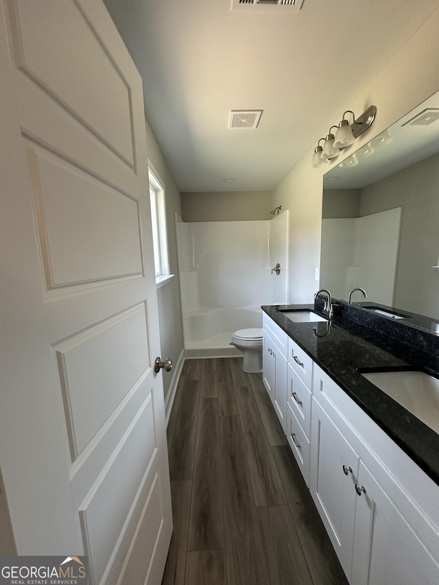 bathroom with vanity, toilet, hardwood / wood-style floors, and walk in shower