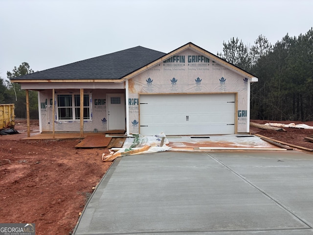 unfinished property featuring a garage, driveway, and a shingled roof