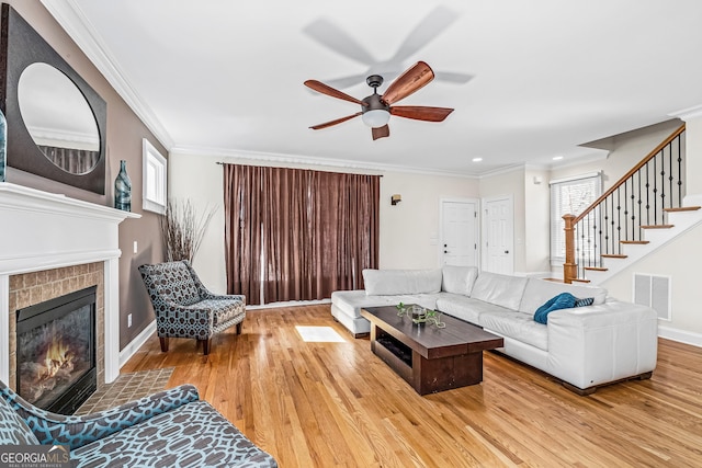 living area featuring stairs, ornamental molding, a tile fireplace, and visible vents