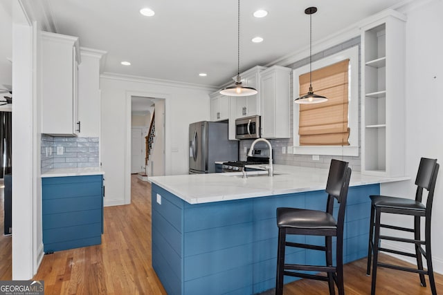 kitchen featuring a breakfast bar area, a peninsula, stainless steel appliances, white cabinetry, and open shelves