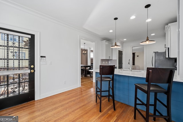 kitchen with appliances with stainless steel finishes, white cabinetry, a sink, and a kitchen bar