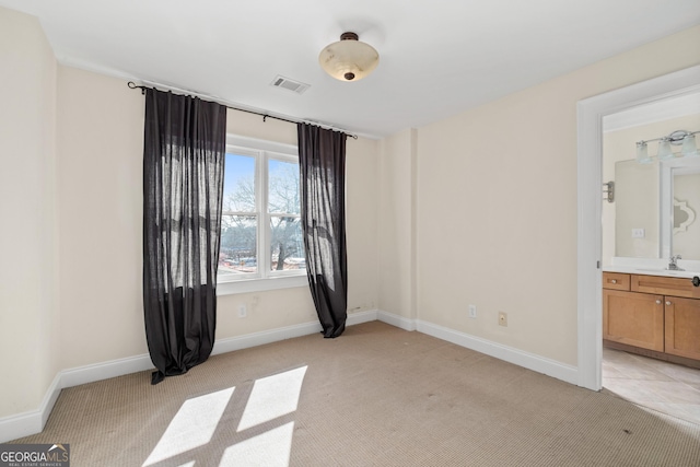 empty room featuring light carpet, baseboards, visible vents, and a sink