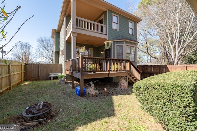 rear view of house with a deck, a fenced backyard, a lawn, and a fire pit