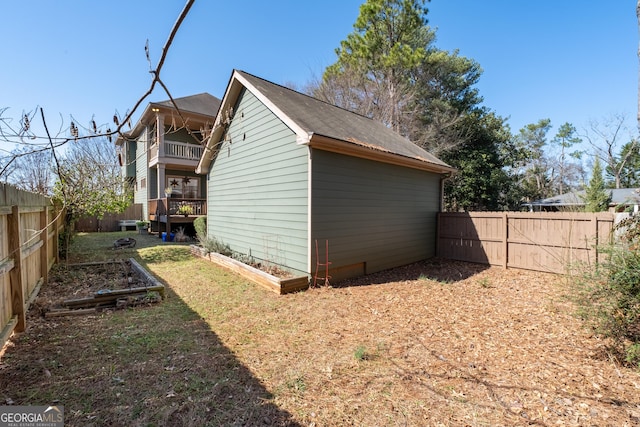 exterior space featuring a fenced backyard, a vegetable garden, and a balcony