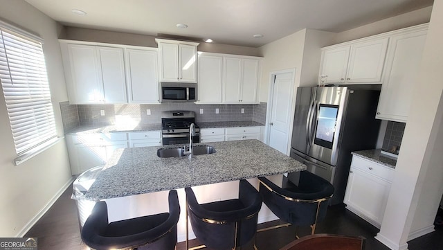 7157 Gladstone, Stonecrest, GA 30038 - kitchen featuring appliances with stainless steel finishes, white cabinetry, light stone counters, and a kitchen breakfast bar