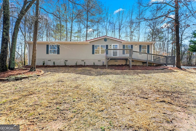 manufactured / mobile home featuring a wooden deck and a front lawn