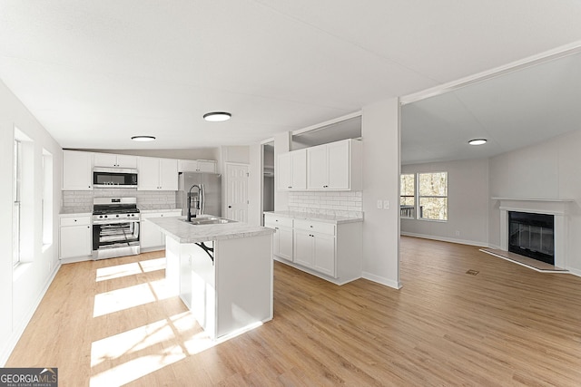 kitchen featuring sink, light hardwood / wood-style flooring, appliances with stainless steel finishes, an island with sink, and white cabinets