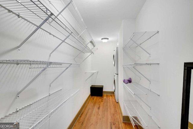 spacious closet featuring stacked washer and dryer and wood-type flooring