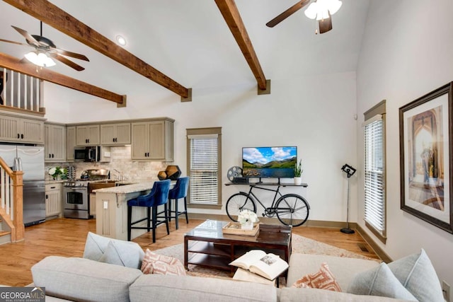 living room featuring beam ceiling, ceiling fan, high vaulted ceiling, and light wood-type flooring