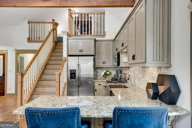 kitchen featuring backsplash, a kitchen bar, light hardwood / wood-style floors, kitchen peninsula, and stainless steel appliances