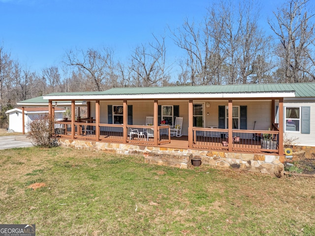 view of front of home featuring covered porch, metal roof, and a front lawn