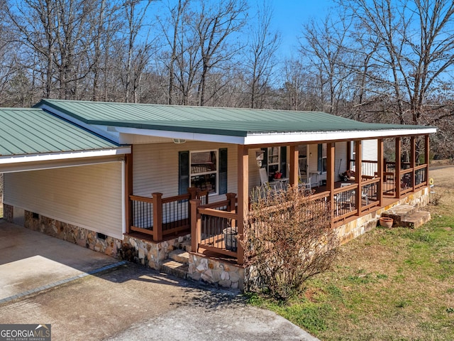 view of front of property with crawl space, covered porch, metal roof, and concrete driveway