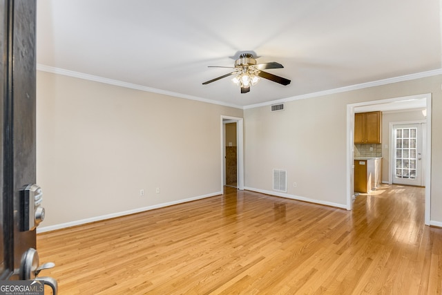 spare room with light wood finished floors, baseboards, visible vents, and ornamental molding