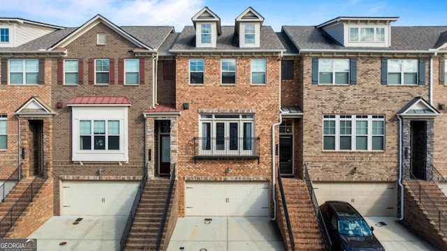 multi unit property featuring a garage, brick siding, and driveway