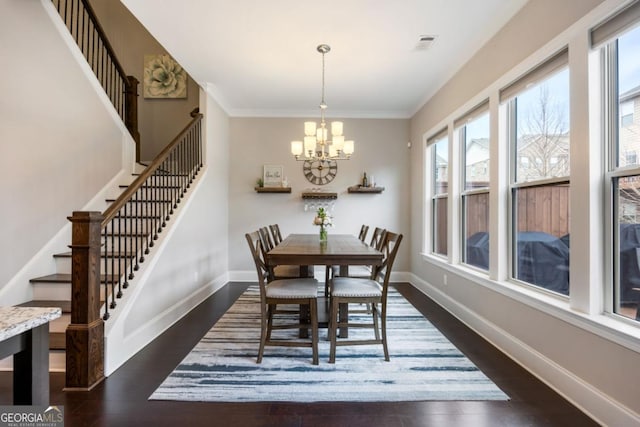 dining area with ornamental molding, dark wood-type flooring, and a notable chandelier