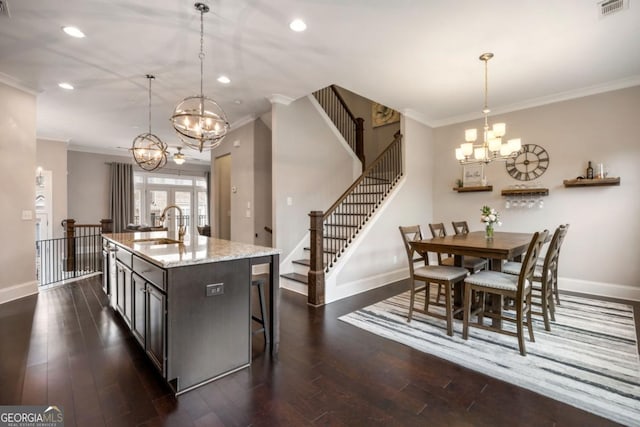 kitchen featuring a notable chandelier, dark hardwood / wood-style floors, pendant lighting, sink, and a kitchen island with sink