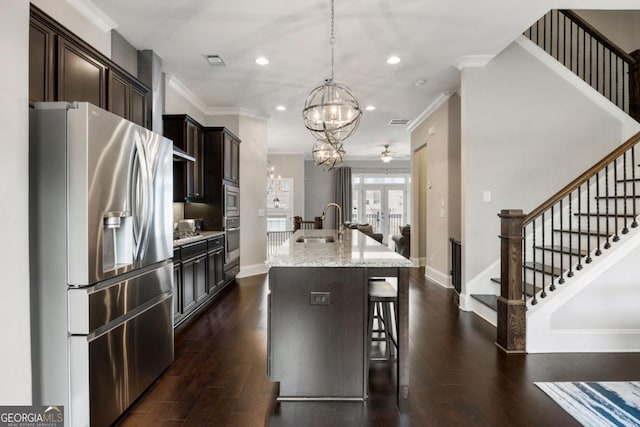 kitchen with an island with sink, hanging light fixtures, a breakfast bar, appliances with stainless steel finishes, and dark hardwood / wood-style floors